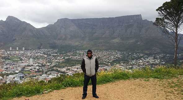 Adam standing on Signal Hill, with Table Mountain behind him. Photo by Waheed Adams.